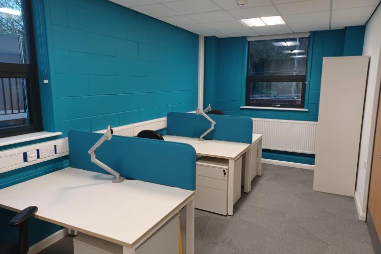 image of desks, vibrant teal wall and tables with equipment