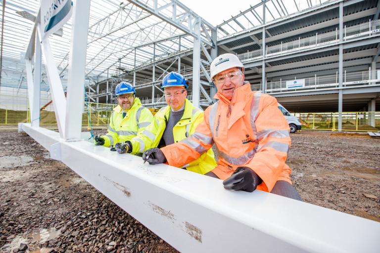 Stephen Burnell, Managing Director MOD Services, Boeing; Air Commander Ian Gale, RAF Lossiemouth;  Bill Robertson, Executive Chairman, Robertson Group sign steelwork at RAF Lossiemouth Boeing facility