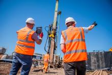 Two Robertson employees looking out onto a construction site photographing construction activity