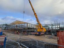 Commercial building under construction with timber and timber roof being craned into place