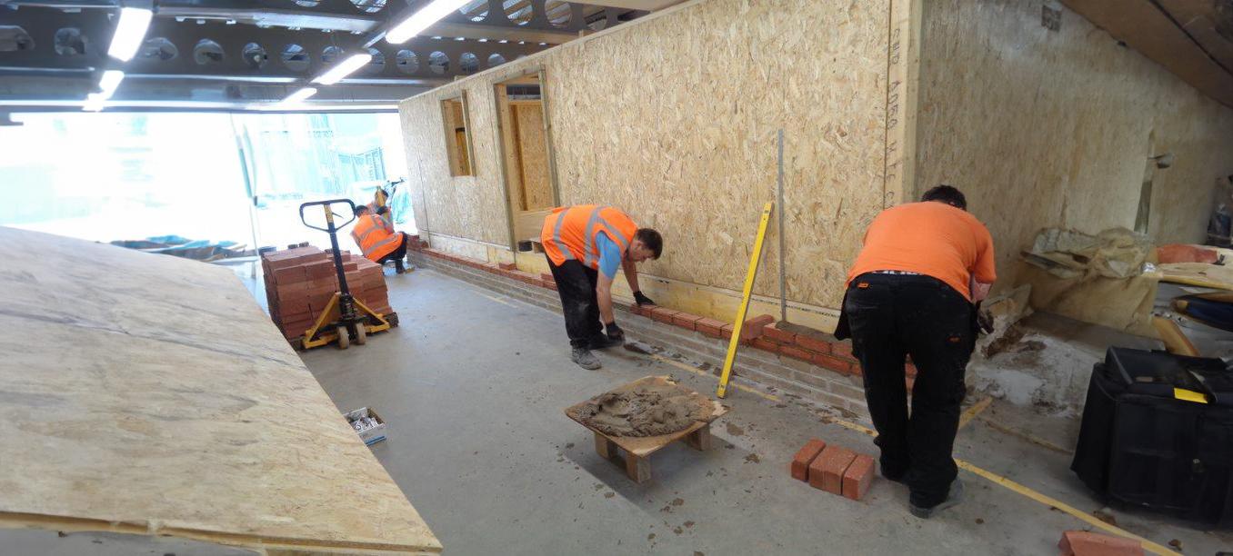 Two men working on brick wall