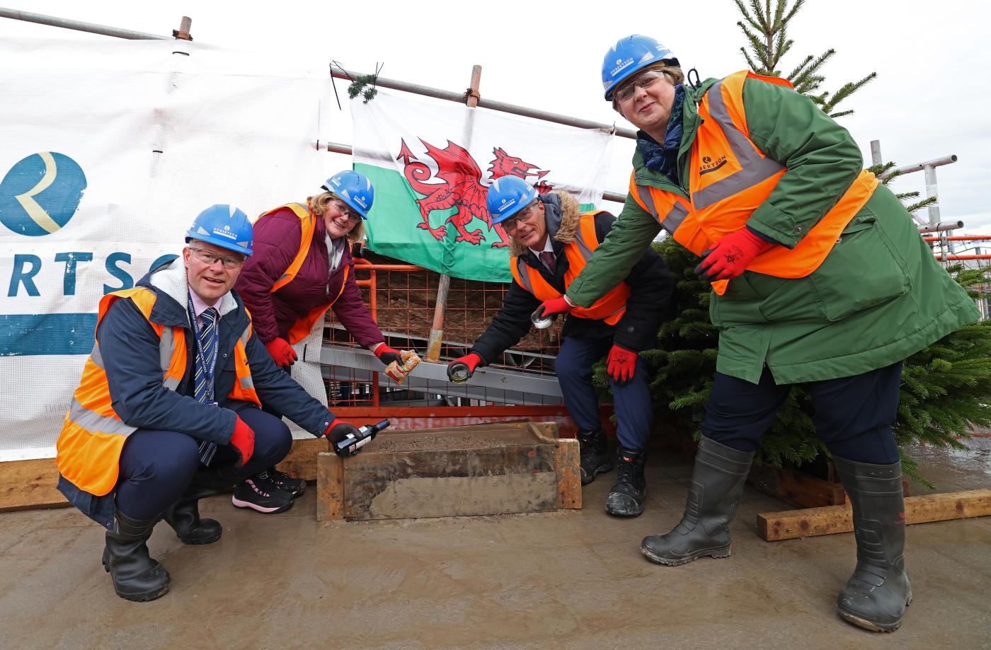 Representatives from local schools and Flintshire County Council putting items into a ceremonial brick as part of Mynydd Isa Campus' topping out