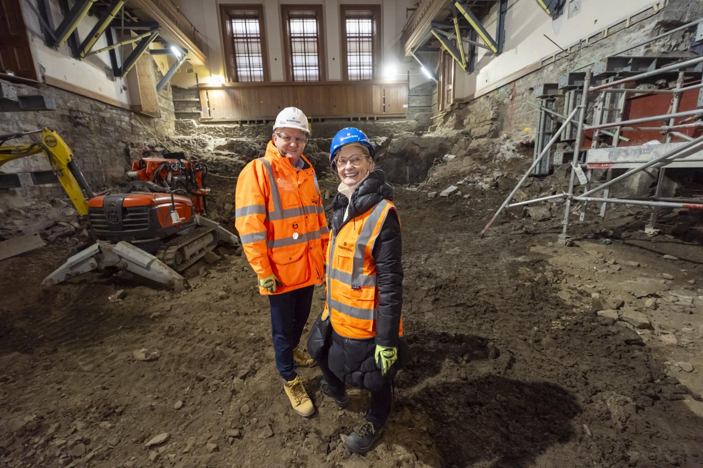 Two people in PPE, one from Robertson Construction and the other from Royal High School Preservation Trust, standing in the grand hall of the National Centre for Music to announce the project commencing.
