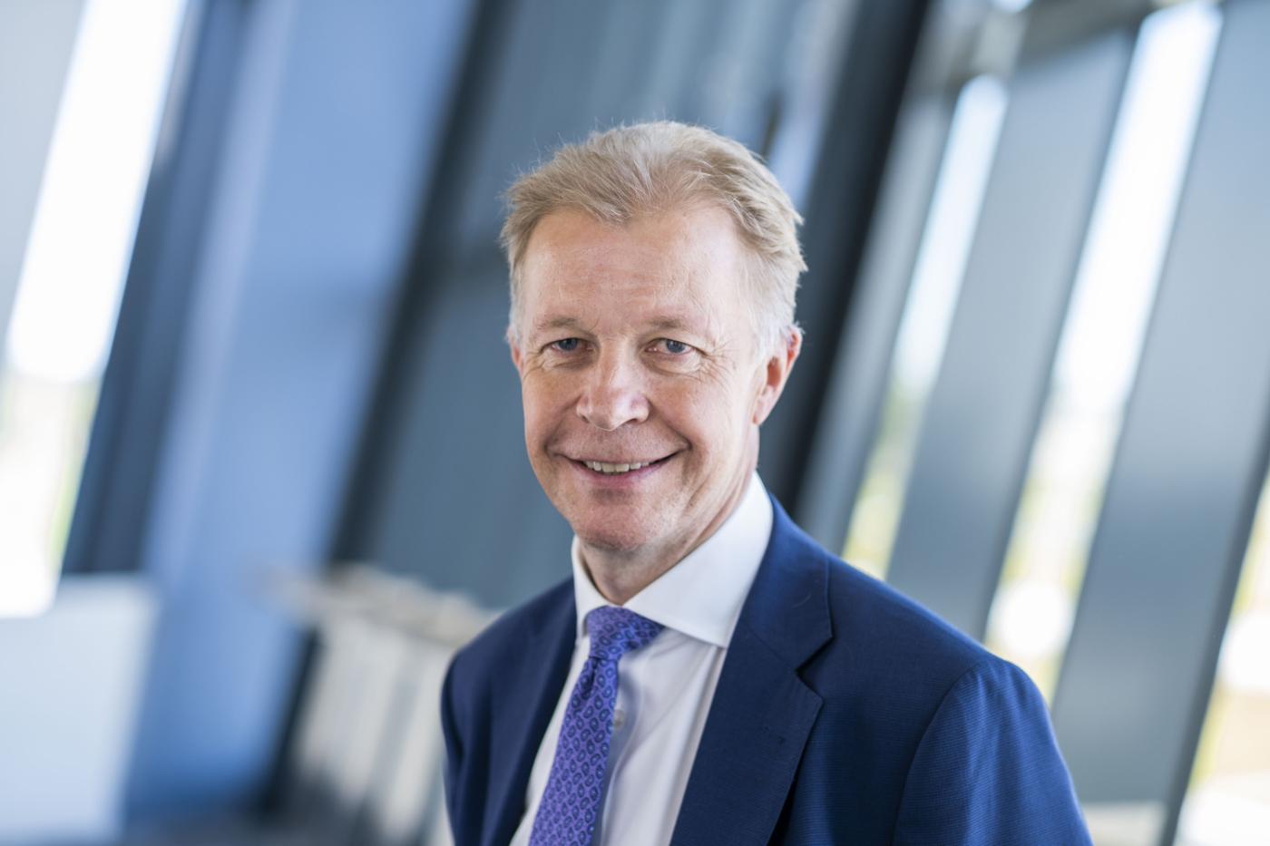 Man with light hair wearing a navy suit and blue tie in front of an industrial background, he is the CEO of RFM, a Robertson Group supported business