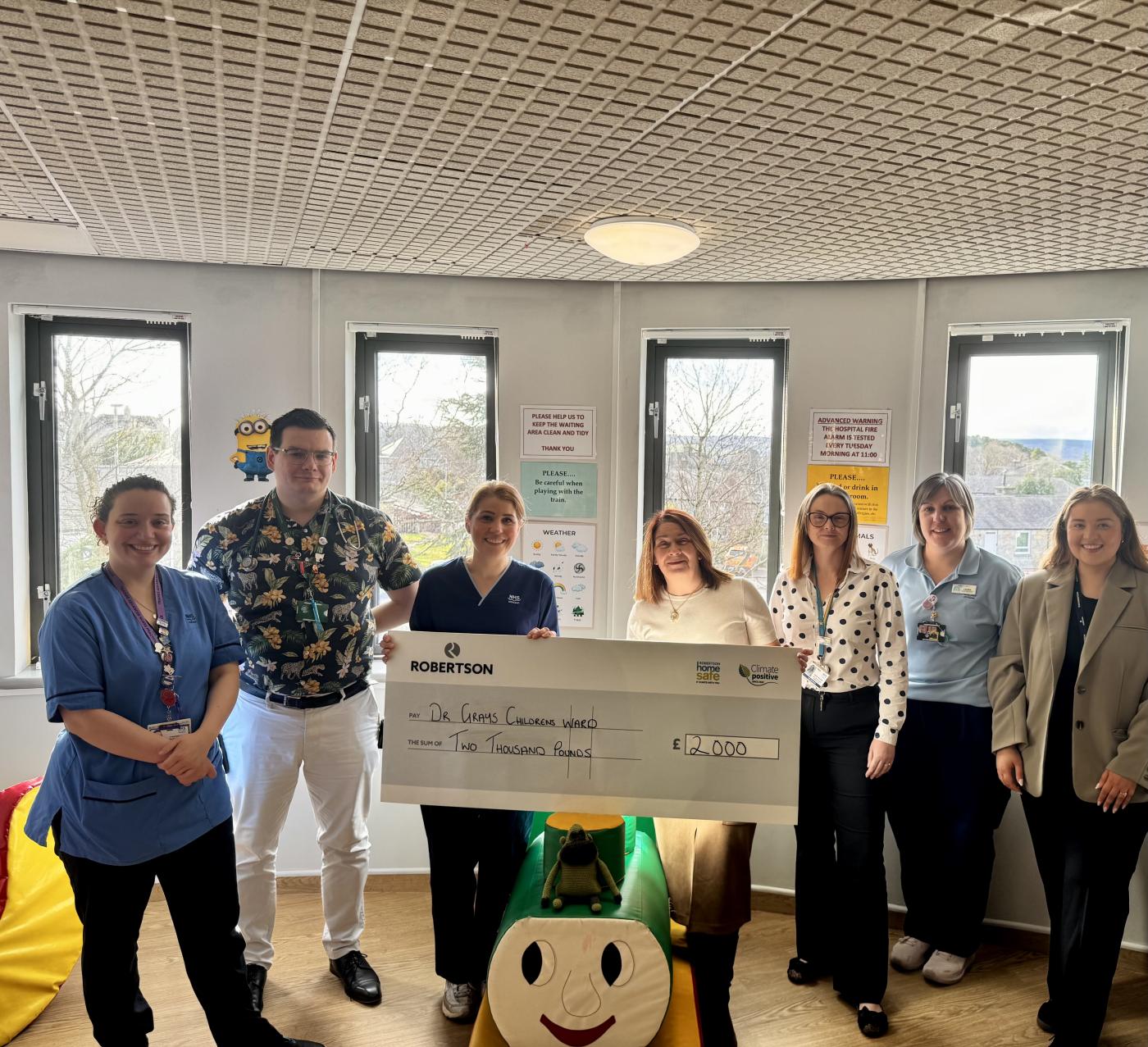Representative from Robertson Property presenting the Children's Ward at Dr Gray's Hospital in Elgin a cheque for £2,000, surrounded by nurses and employees among children's toys