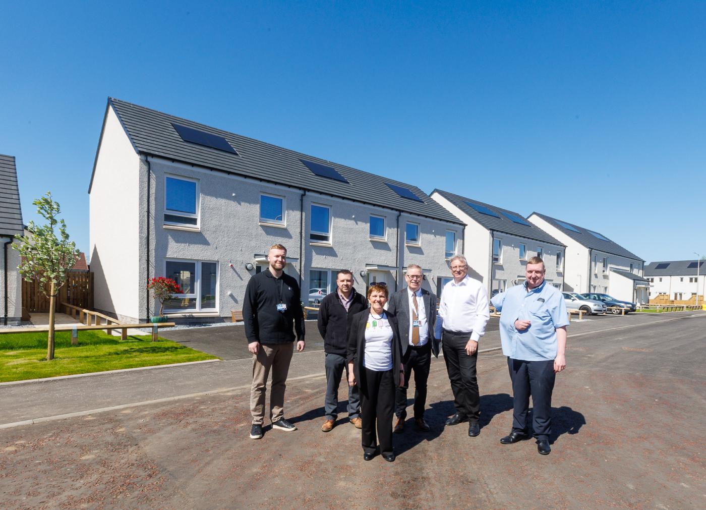 People stood in front of new affordable housing with blue skies, marking the handover of the Viewfield development delivered by Robertson for Fife Council