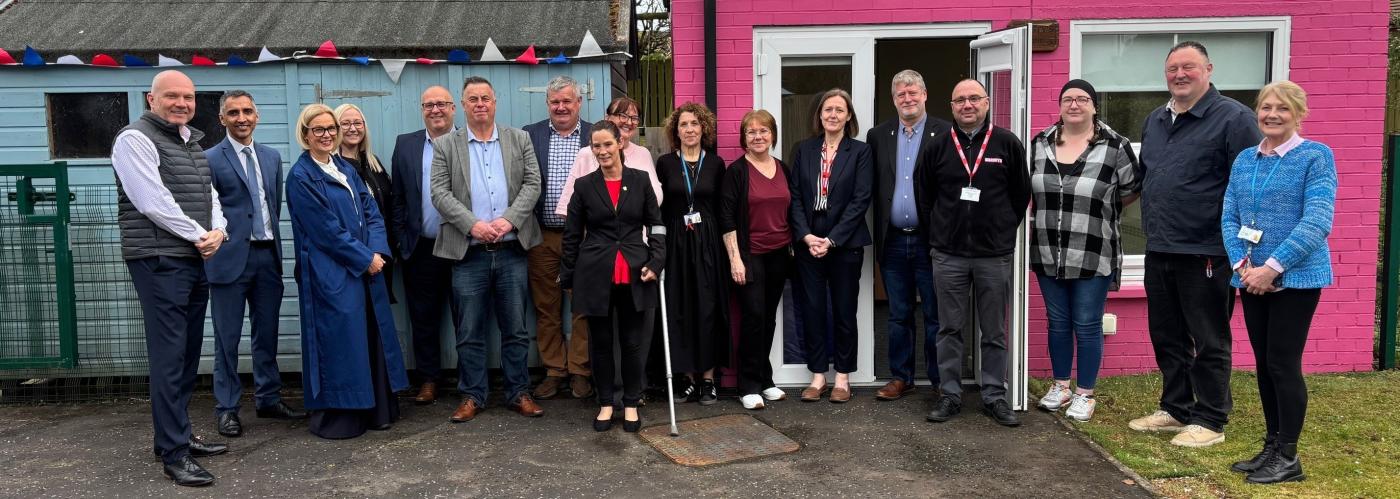 A group of people in front of coloured sheds
